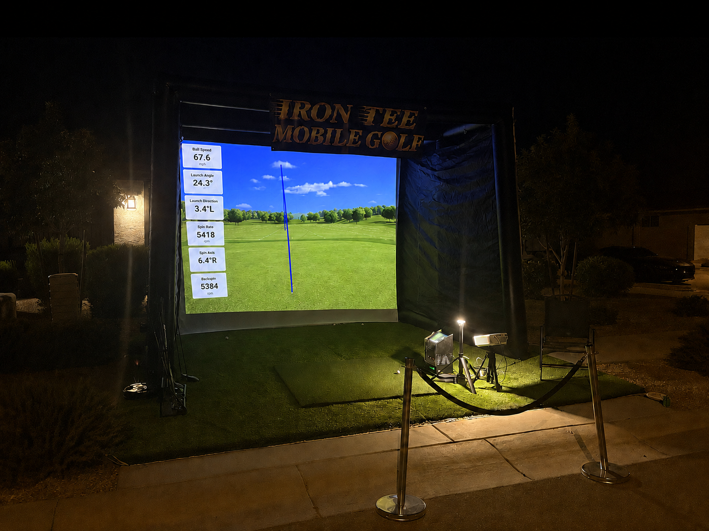 IRON TEE Mobile Golf simulator glowing at night with live shot data at an outdoor event in Arizona