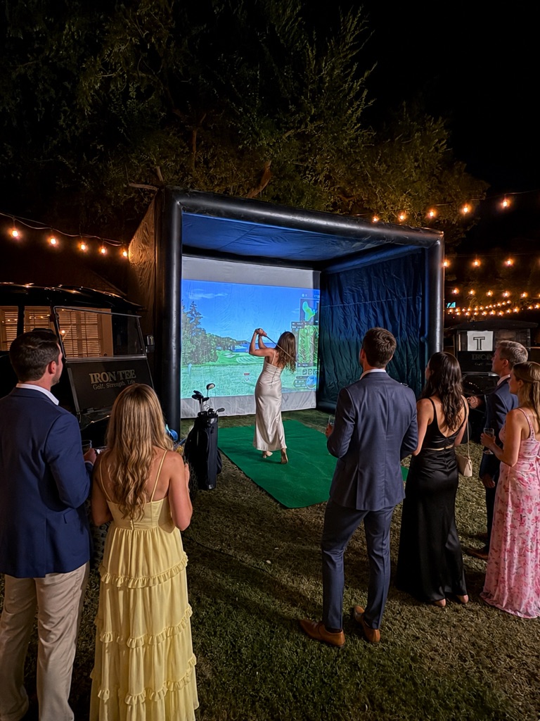 Private party with guests enjoying outdoor mobile golf simulator at night
